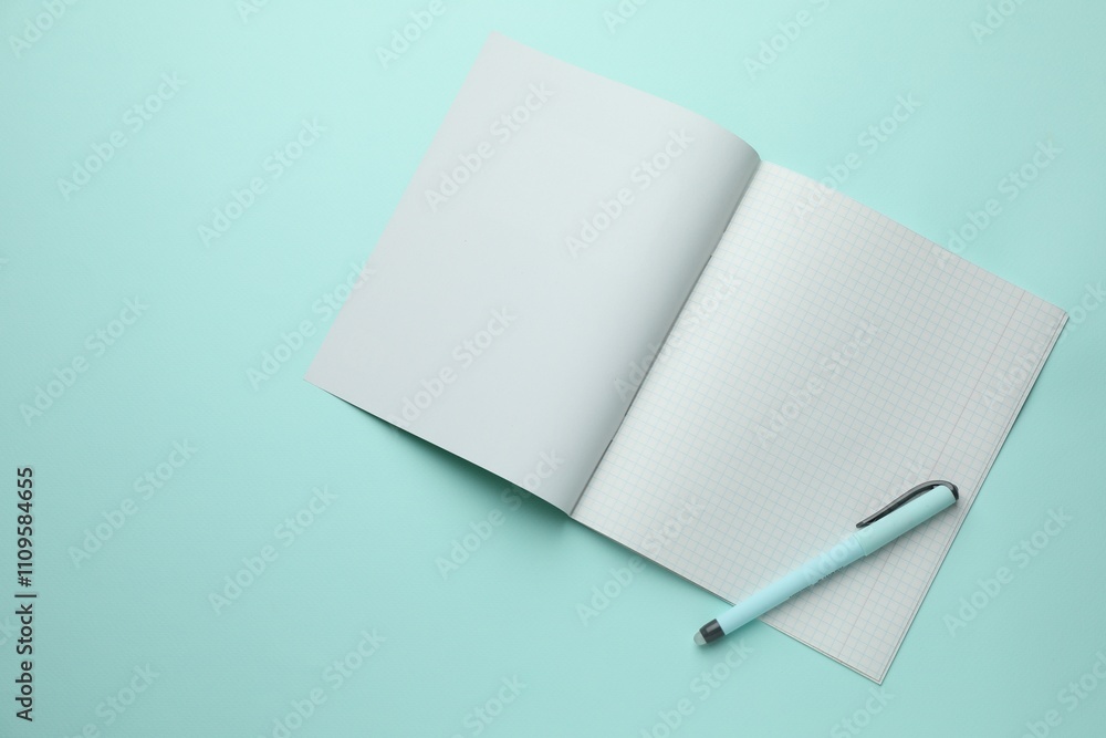 Open copybook with checkered sheets of paper and pen on light blue background, top view. School stationery Open copybook with checkered sheets of paper and pen on light blue background, top view. School stationery