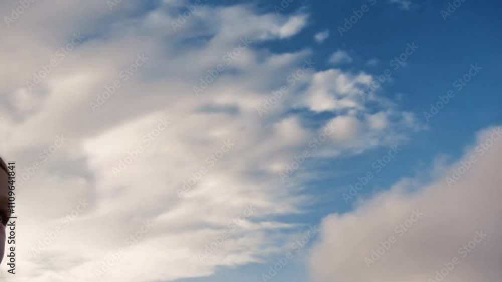 A slow-motion shot captures a girl gazing upwards at the sky, the clouds parting to reveal a vast expanse above. The light streaming through creates a breathtaking atmosphere, perfect for a calming an A slow-motion shot captures a girl gazing upwards at the sky, the clouds parting to reveal a vast expanse above. The light streaming through creates a breathtaking atmosphere, perfect for a calming an