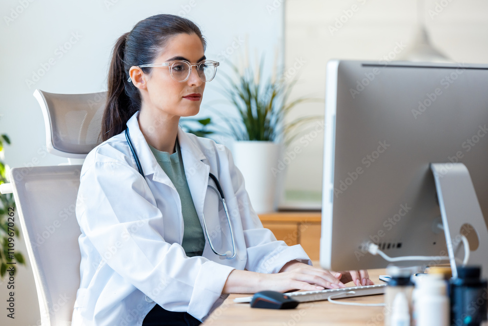 Smiling female doctor working with her laptop in the consultation. Smiling female doctor working with her laptop in the consultation.