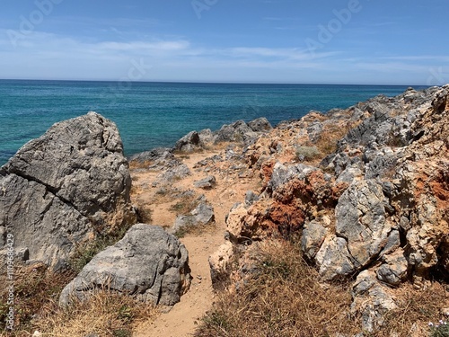 Footpath through the rough rocks at a cretian beach photo