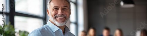 A man with a smile on his face is standing in front of a group of people. He is wearing a blue shirt and he is happy