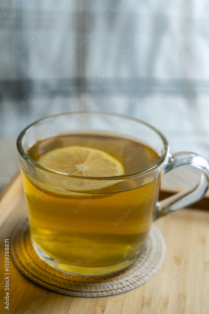 A cup of green tea with lemon on a cozy tablecloth, highlighting health and comfort. A cup of green tea with lemon on a cozy tablecloth, highlighting health and comfort.