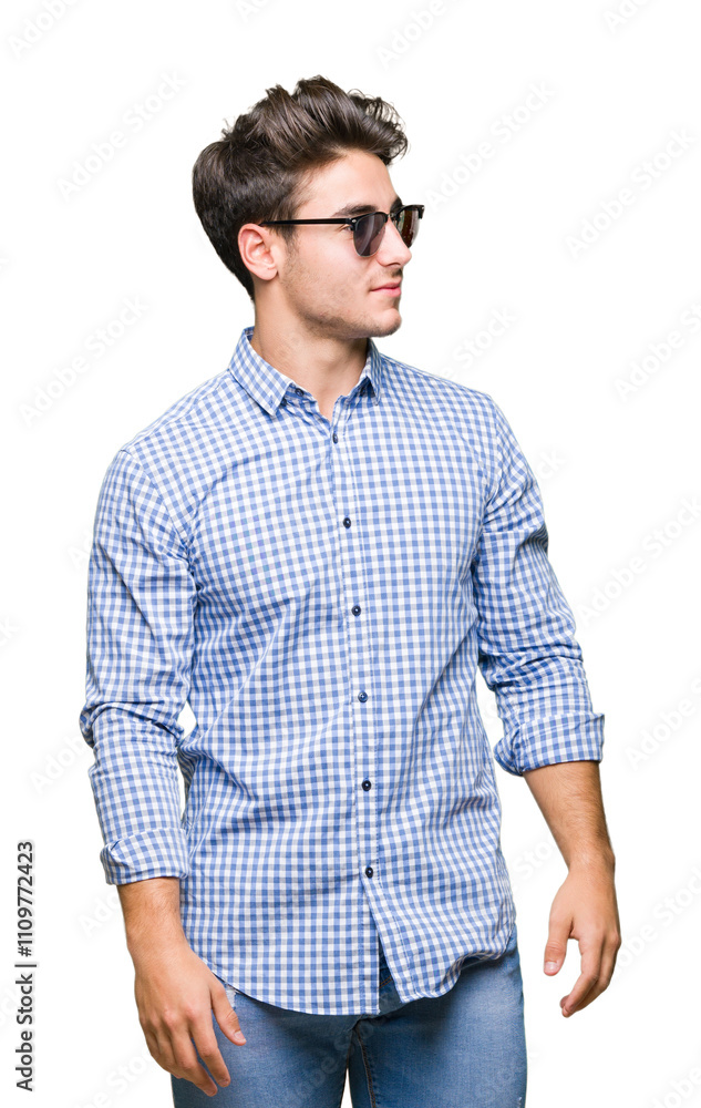 Young handsome man wearing sunglasses over isolated background looking away to side with smile on face, natural expression. Laughing confident. Young handsome man wearing sunglasses over isolated background looking away to side with smile on face, natural expression. Laughing confident.