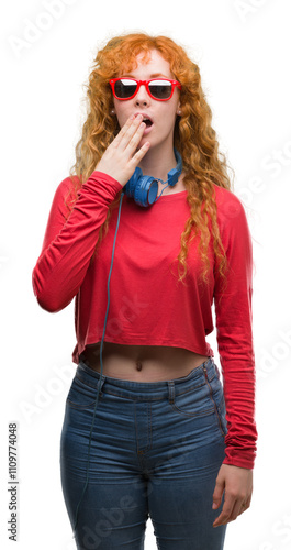 Young redhead woman wearing headphones cover mouth with hand shocked with shame for mistake, expression of fear, scared in silence, secret concept