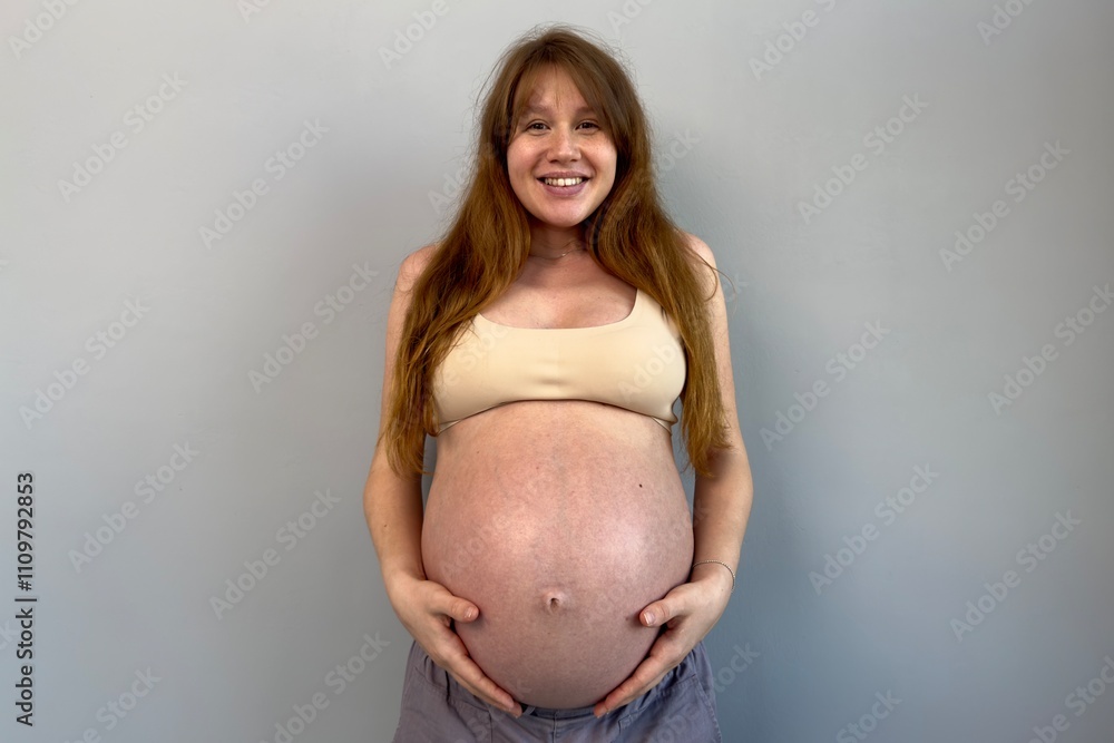 Happy pregnant young woman on gray background in lingerie Happy pregnant young woman on gray background in lingerie