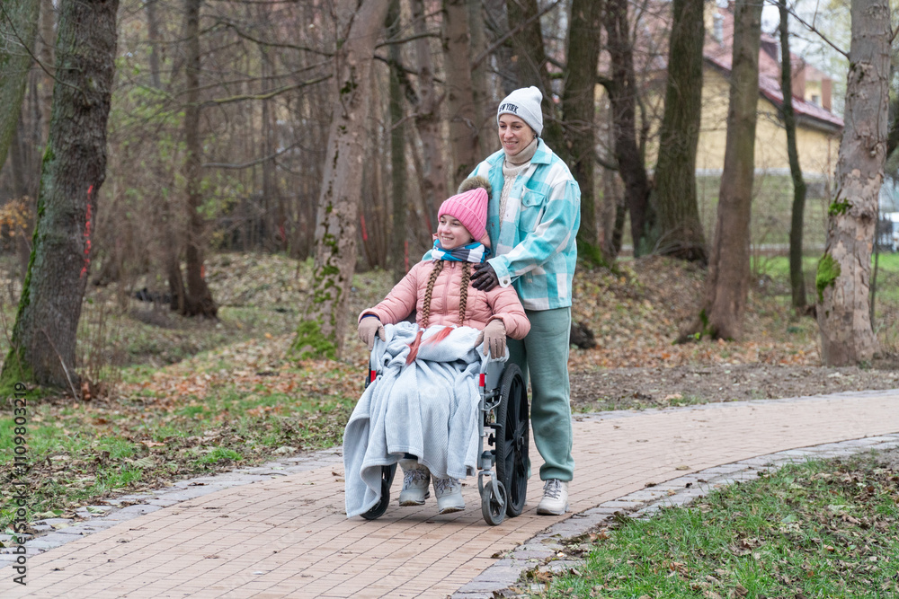 disabled girl, wheelchair, family walk in the park with a disabled child, mother with son and daughter, autumn, winter in Europe disabled girl, wheelchair, family walk in the park with a disabled child, mother with son and daughter, autumn, winter in Europe