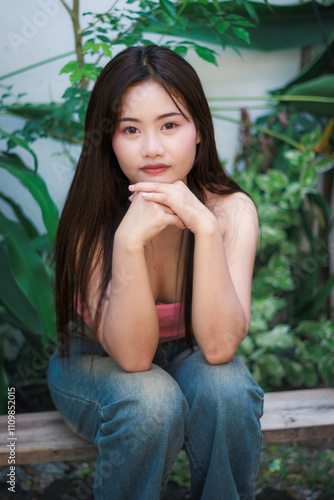 Smiling brunette woman sitting outdoors in a tropical park during summer. photo