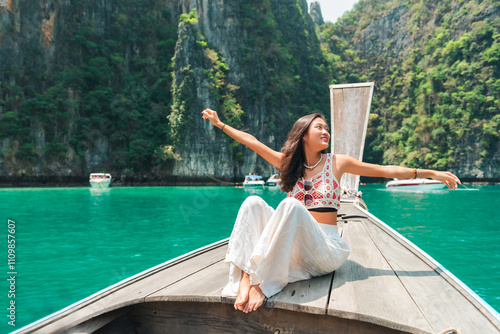 Summer travel nature beach holiday vacation. Happy Asian woman enjoy outdoor lifestyle travel the sea sitting on wooden boat and looking beautiful nature of tropical island beach at Krabi, Thailand.