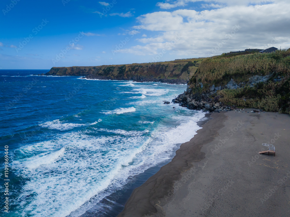 Obraz premium Aerial drone view of Azores islands coast with black sand beach. Praia dos Moinhos landscape in Sao Miguel, Portugal. Atlantic ocean shore with cliffs