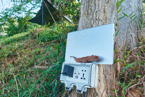 charging a laptop in nature, the outlet is installed on a tree in the campsite