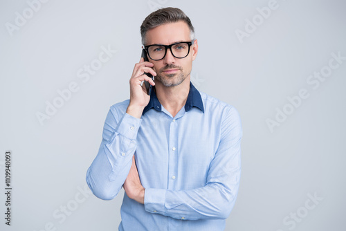 Business communication. Business man having phone call isolated on grey. Businessman using phone. Man phone conversation in glasses. Mature businessman with phone. Busy signal