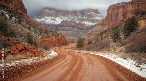 A winding dirt road leads through a snow-covered canyon in a scenic landscape. photo