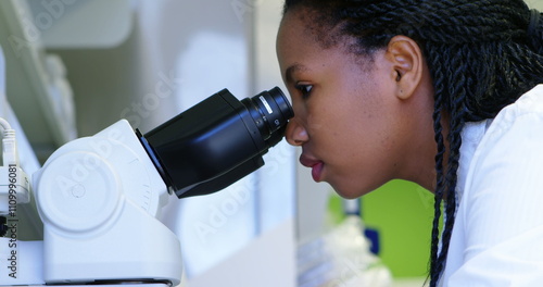 Scientist looking through microscope in laboratory