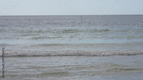 A serene view of gentle ocean waves lapping against the shore under a clear blue sky, evoking tranquility and the peacefulness of nature.