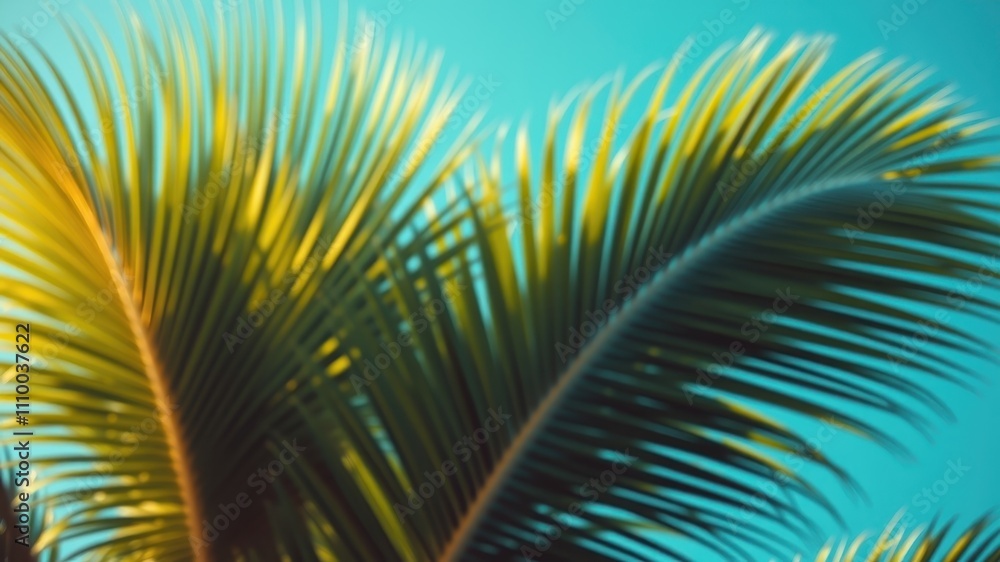 Fototapeta premium A blurred image of tropical palm leaves against a vibrant blue sky, showcasing the delicate beauty of nature in a soft and ethereal light.