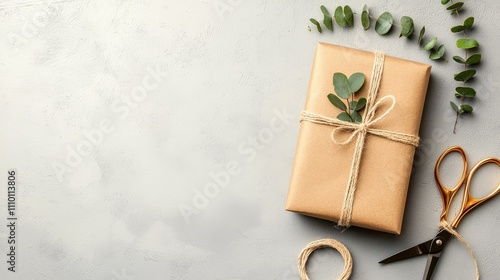 Gift wrapped in eco-friendly brown paper with eucalyptus accents and twine, accompanied by scissors and extra twine on a modern concrete background.