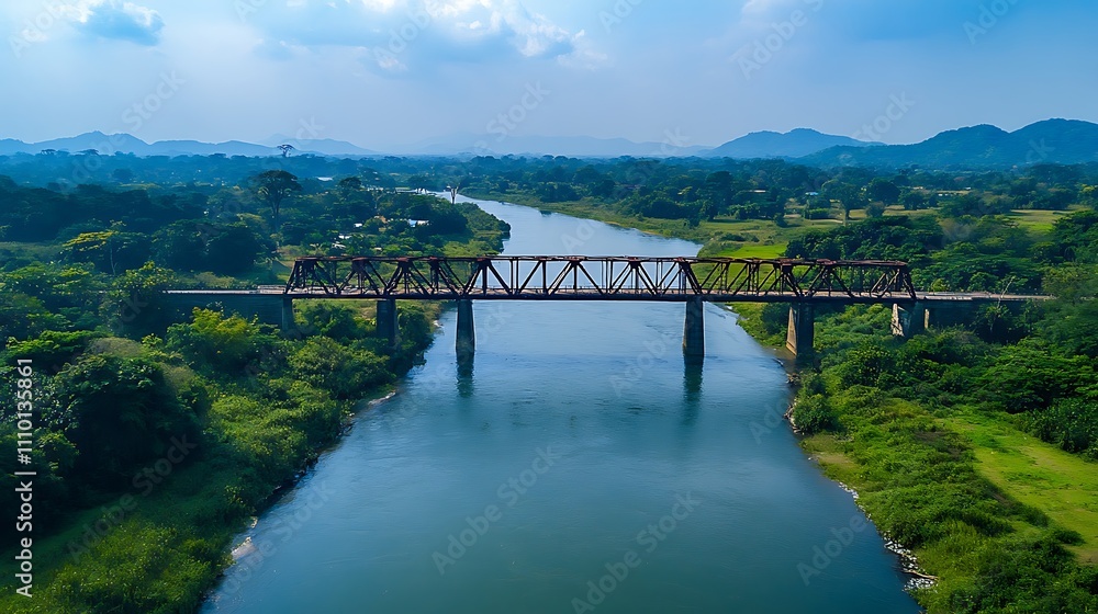 Aerial view of a rusty railway bridge spanning a tranquil river amidst lush green landscape. Aerial view of a rusty railway bridge spanning a tranquil river amidst lush green landscape.