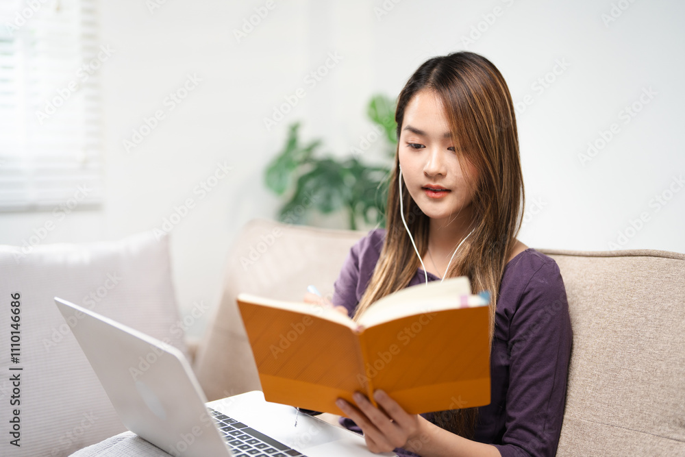 young asian female in earphones writing and taking note look at laptop screen study online on gadget. Happy female in earphones work distant on computer. Education concept. young asian female in earphones writing and taking note look at laptop screen study online on gadget. Happy female in earphones work distant on computer. Education concept.