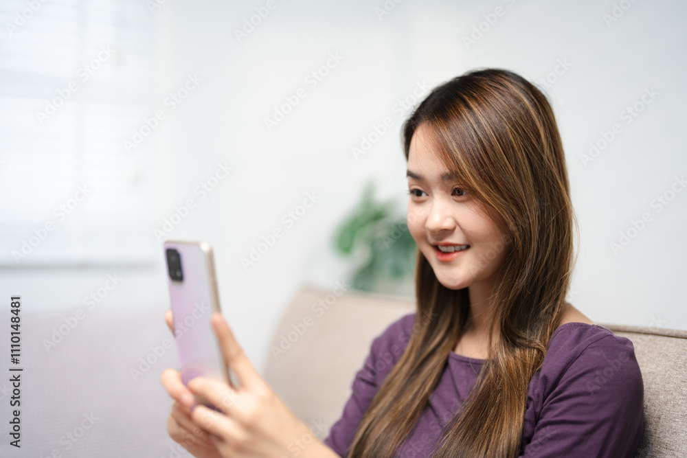 Happy asian teen girl holding cell phone using smartphone device at home. Smiling young asian woman blogger subscribing new social media, buying in internet, ordering products online in apps. Happy asian teen girl holding cell phone using smartphone device at home. Smiling young asian woman blogger subscribing new social media, buying in internet, ordering products online in apps.