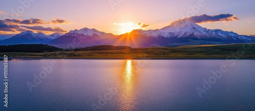 Aerial view of serene lake and majestic mountains at sunset with vibrant colors reflecting on water surface