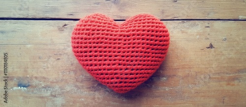 Crochet knit red heart resting on a rustic wooden surface with a vintage filter evoking warmth and nostalgia in a handcrafted aesthetic photo