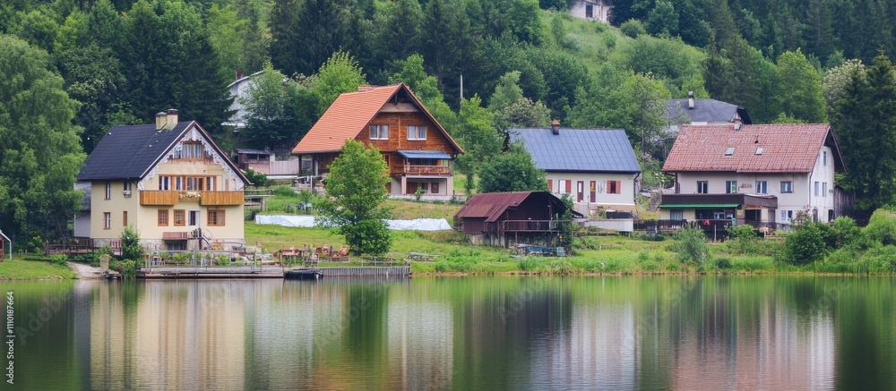 Charming lakeside village with rustic houses surrounded by lush greenery in a peaceful rural setting Charming lakeside village with rustic houses surrounded by lush greenery in a peaceful rural setting