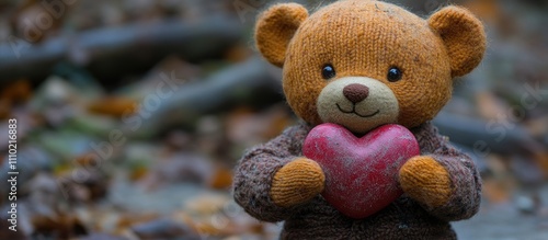 Teddy bear holding a heart symbolizing love and affection in a cozy outdoor setting during autumn foliage