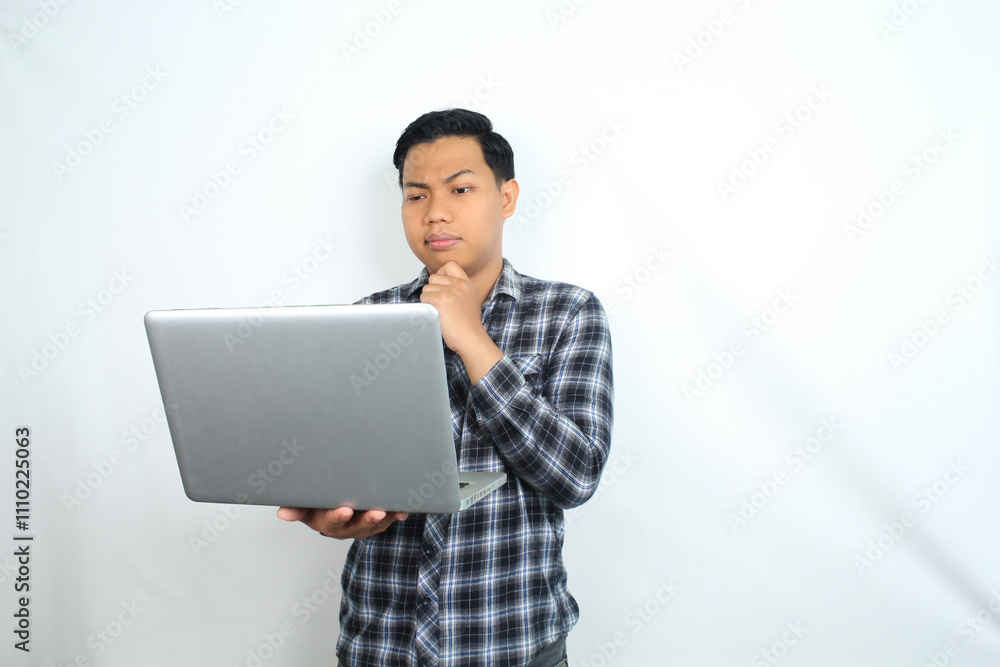 thoughtful asian man holding laptop looks confused and curious isolated on white background, male wearing plaid shirt using computer thoughtful asian man holding laptop looks confused and curious isolated on white background, male wearing plaid shirt using computer