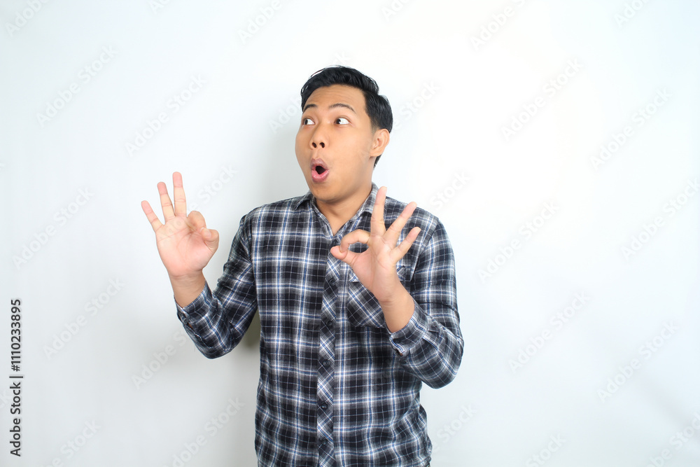 funny asian man showing okay symbol using hand with surprised and shocked expression isolated on white funny asian man showing okay symbol using hand with surprised and shocked expression isolated on white