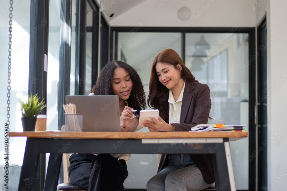Two beautiful young businesswomen using a calculator to calculate and analyze a real estate project that they are looking for. Two beautiful young businesswomen using a calculator to calculate and analyze a real estate project that they are looking for.