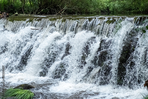 small dam on a river, foaming water coming over a small waterfall from a dam. photo