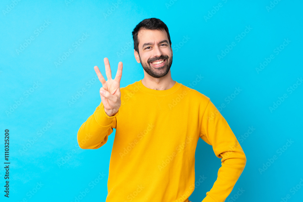 Young caucasian man over isolated blue background happy and counting three with fingers Young caucasian man over isolated blue background happy and counting three with fingers