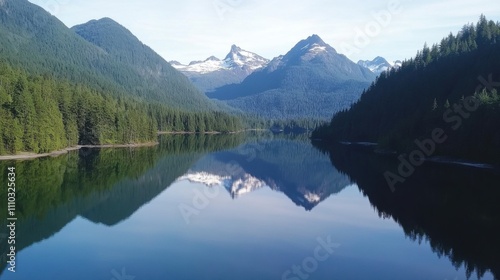 Stunning reflection of mountains in calm lake surrounded by lush forest in the Pacific Northwest during daytime