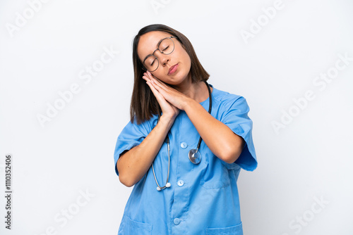 Young surgeon doctor woman isolated on white background making sleep gesture in dorable expression photo