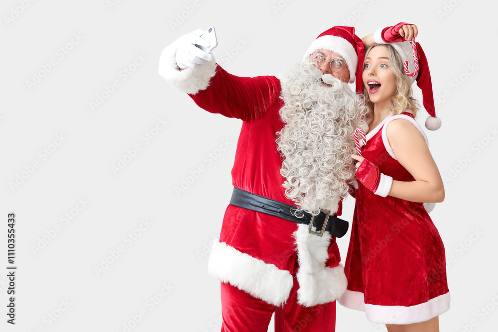 Santa Claus and beautiful woman taking selfie on white background Santa Claus and beautiful woman taking selfie on white background