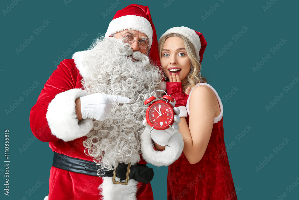 Santa Claus with beautiful woman pointing at alarm clock on green background Santa Claus with beautiful woman pointing at alarm clock on green background