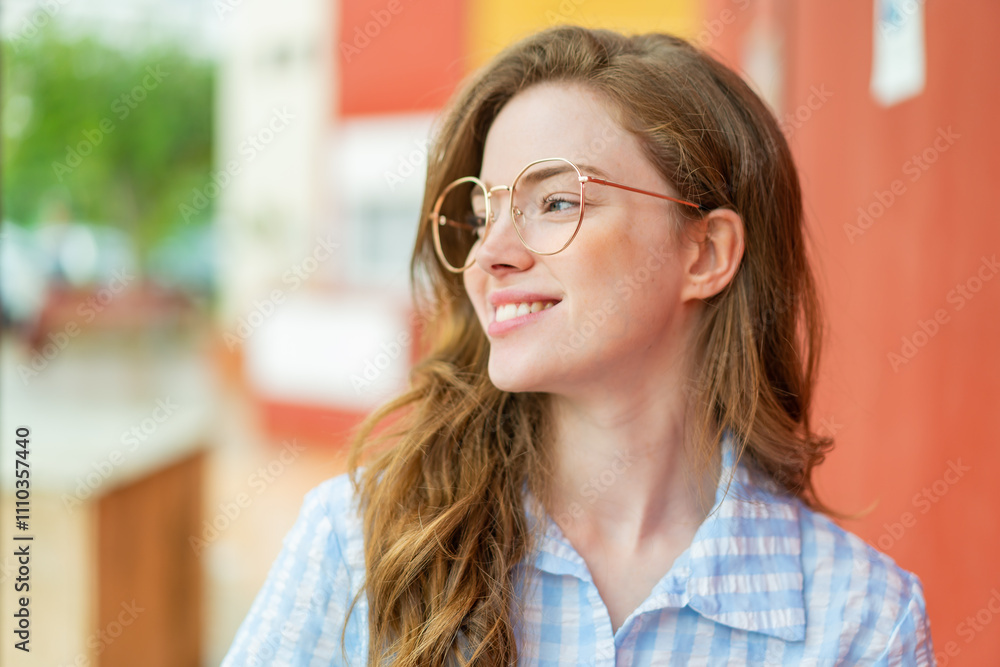 Young redhead woman at outdoors With glasses with happy expression Young redhead woman at outdoors With glasses with happy expression