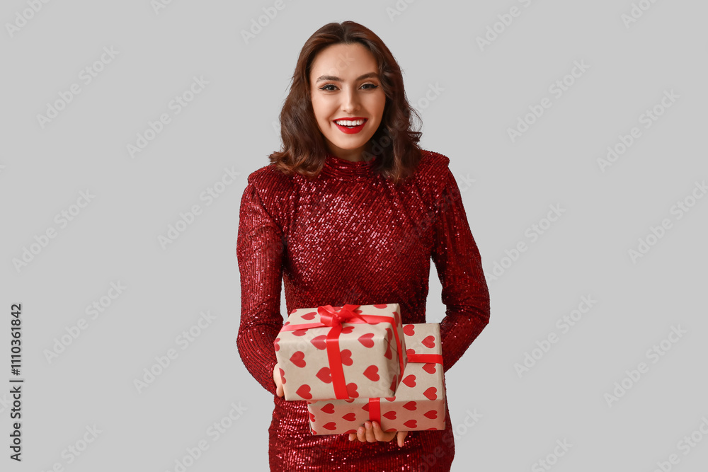 Beautiful young woman with gift boxes on grey background Beautiful young woman with gift boxes on grey background