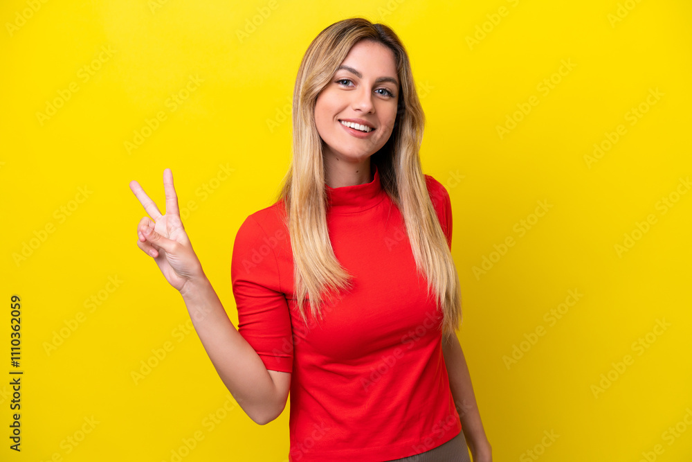 Young Uruguayan woman isolated on yellow background smiling and showing victory sign Young Uruguayan woman isolated on yellow background smiling and showing victory sign
