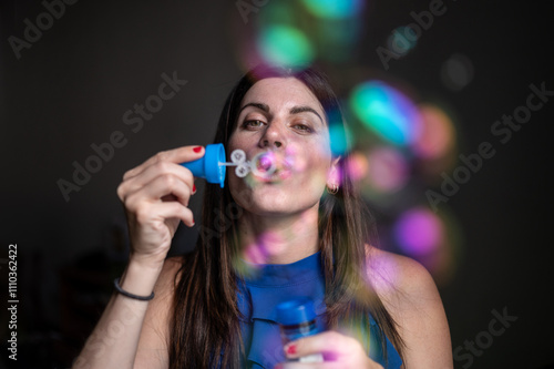 Interior portrait of an attractive caucasian woman in her thirties blowing soap bubbles photo