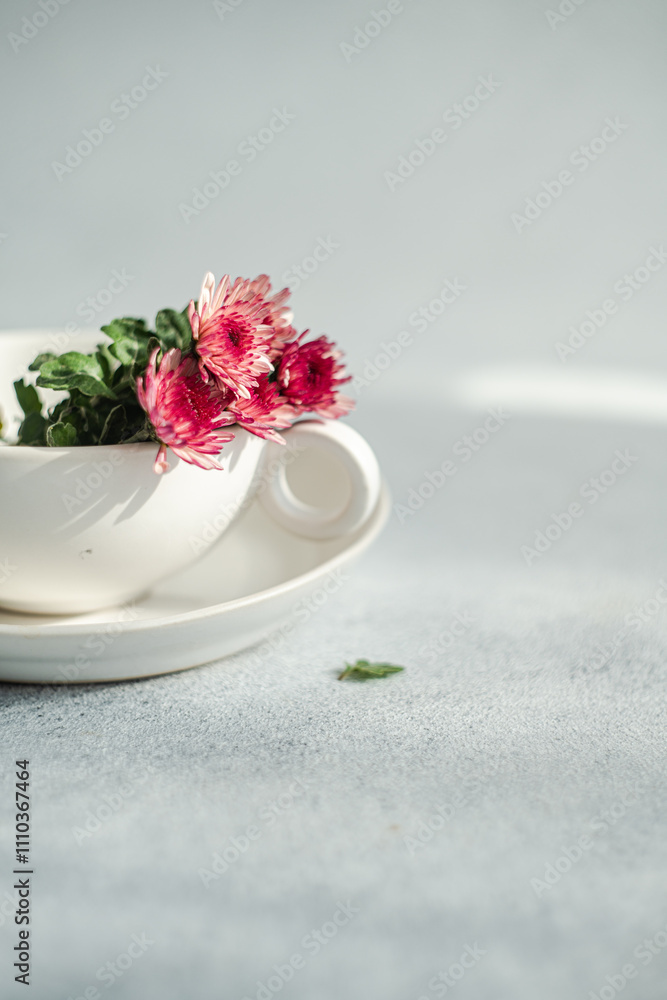 Delicate Pink Flowers in White Teacup on Soft Gray Background Delicate Pink Flowers in White Teacup on Soft Gray Background