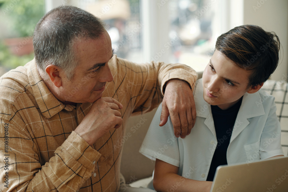 Fototapeta premium Grandfather talking to his grandchild while he using laptop