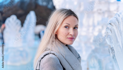 Woman with frost tipped hair poses in front of stunning ice sculpture display during winter festival photo