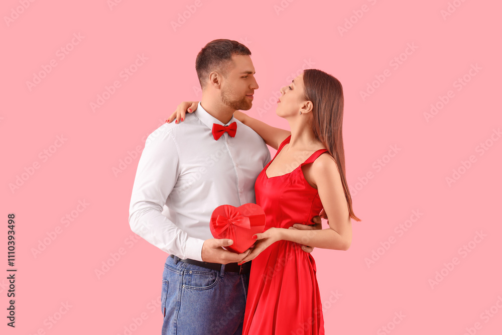 Lovely couple with heart-shaped gift box on pink background. Valentine's Day celebration Lovely couple with heart-shaped gift box on pink background. Valentine's Day celebration