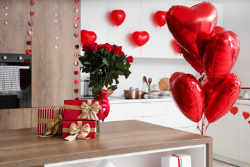 Gift boxes and bouquet of roses on wooden table in kitchen, closeup. Valentine's Day celebration