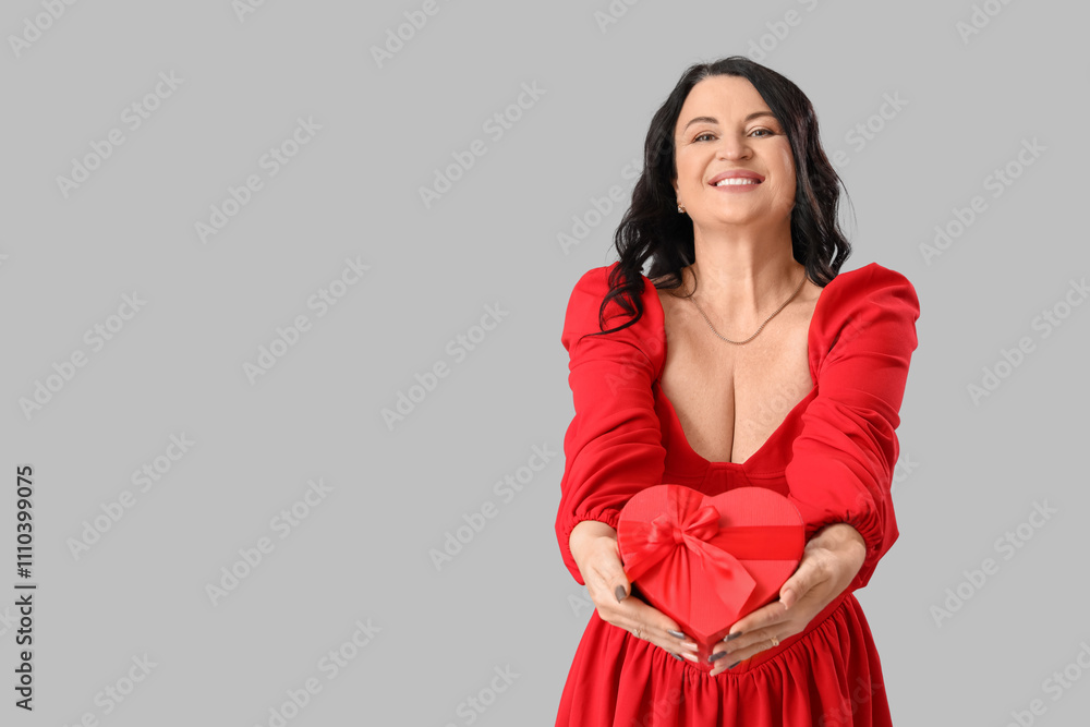 Beautiful happy mature woman with gift box on grey background. Valentine's Day celebration Beautiful happy mature woman with gift box on grey background. Valentine's Day celebration