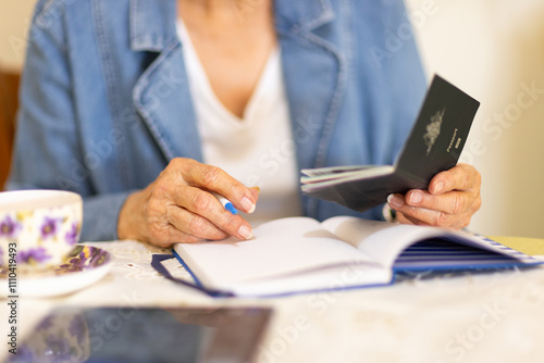 anonymous elderly person making travel plans holding a passport photo