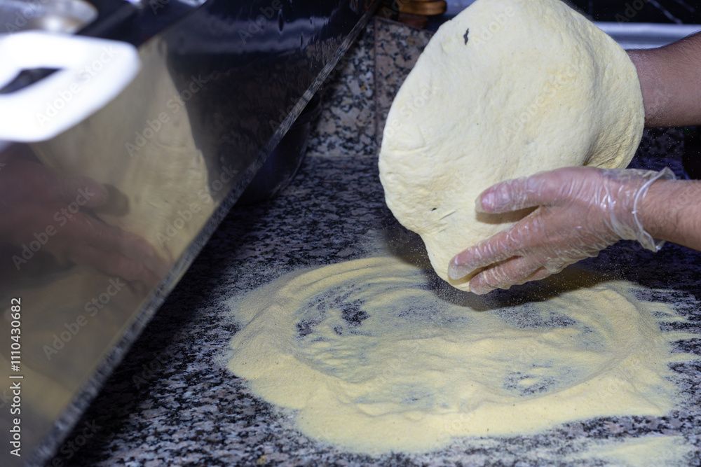 A moment of pure craftsmanship: the pizza maker gently stretches the dough, ready for the most flavorful toppings.