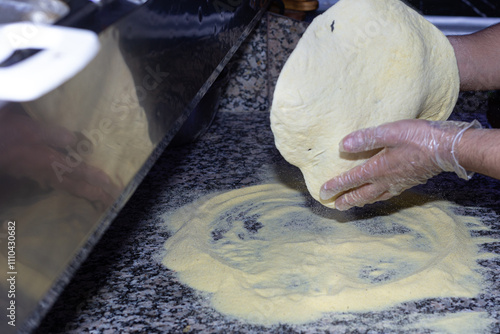 Obraz na płótnie A moment of pure craftsmanship: the pizza maker gently stretches the dough, ready for the most flavorful toppings. w salonie