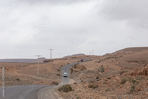 Obraz na płótnie Empty Moroccan landscape with a winding asphalt road and scattered vegetation. w salonie